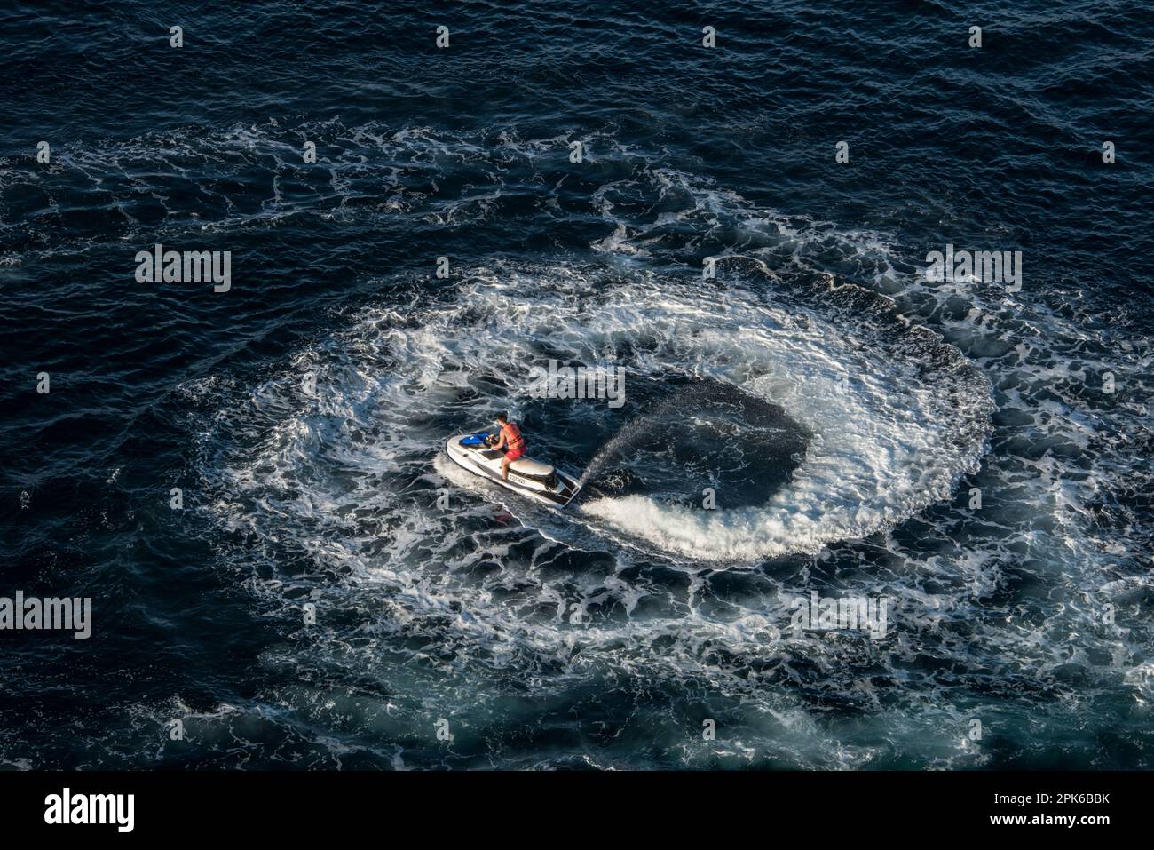 Ein junger Mann (nicht identifizierbar) fährt auf einem persönlichen Jetski-Wasserfahrzeug und bildet einen Kreis unter einem Kreuzfahrtschiff, Cabo San Lucas, Mexiko Stockfoto