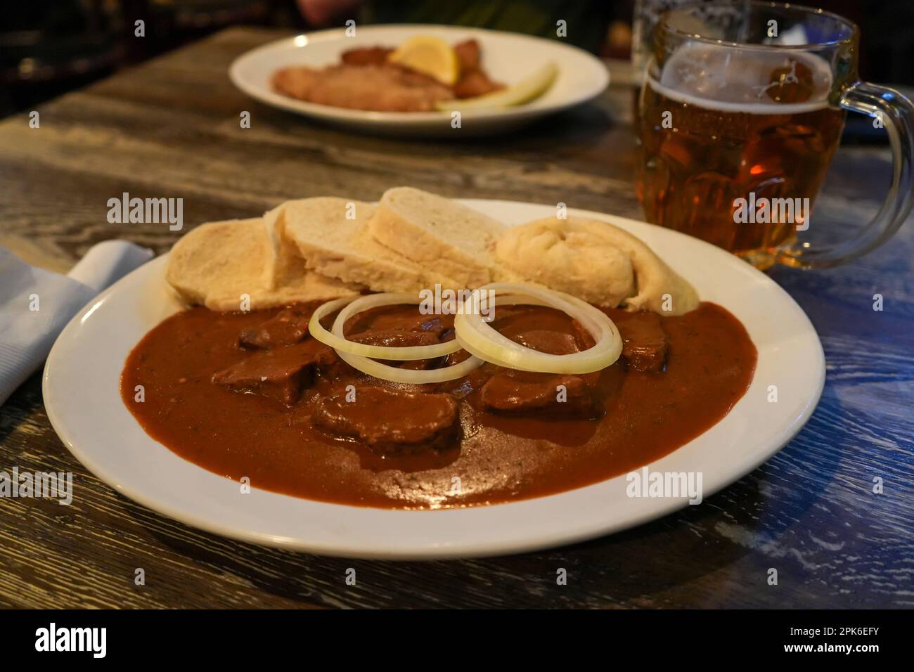 Rindergulasch mit Brotknödeln, garniert mit frischen weißen Zwiebeln. Weiße Platte. Tschechisch, Ostereuropäisch, Ukrainisch, Russisch, Deutsch, Polnisch Stockfoto