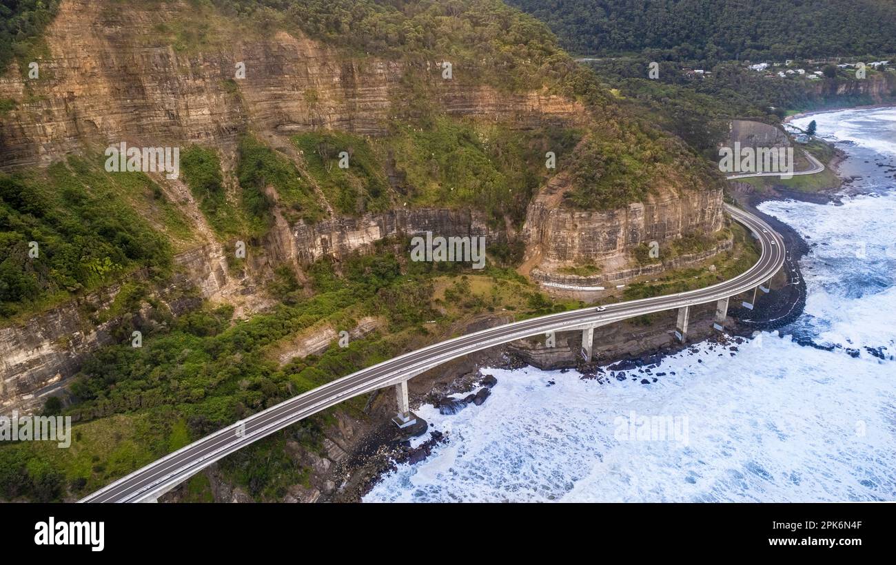 Ein Luftblick auf die Seacliff Bridge entlang der Küste am Pazifischen Ozean in Wollongong, New South Wales, Australien mit Meereswellen. Stockfoto