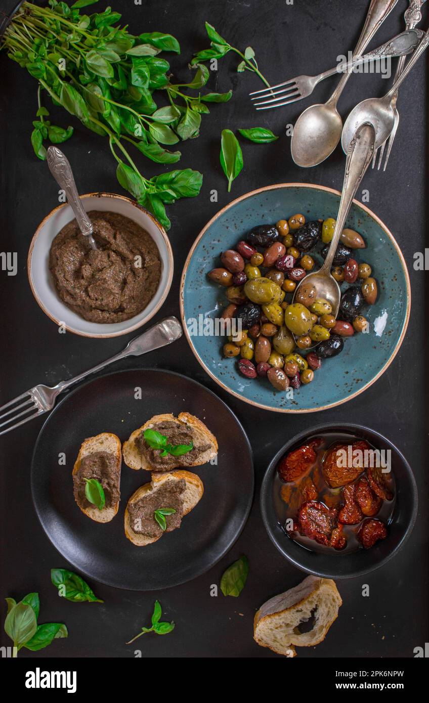 Tisch serviert mit Brot, Tapenade, gemischten Oliven, getrockneten Tomaten in Olivenöl und Basilikum. Esstisch mit französischen provence-Vorspeisen und Canapés Stockfoto