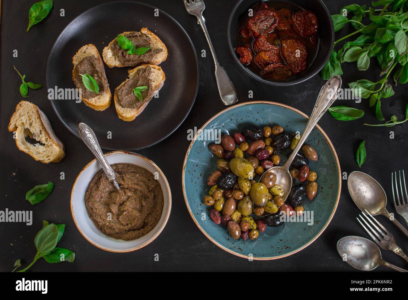 Tisch serviert mit Brot, Tapenade, gemischten Oliven, getrockneten Tomaten in Olivenöl und Basilikum. Esstisch mit französischen provence-Vorspeisen und Canapés Stockfoto