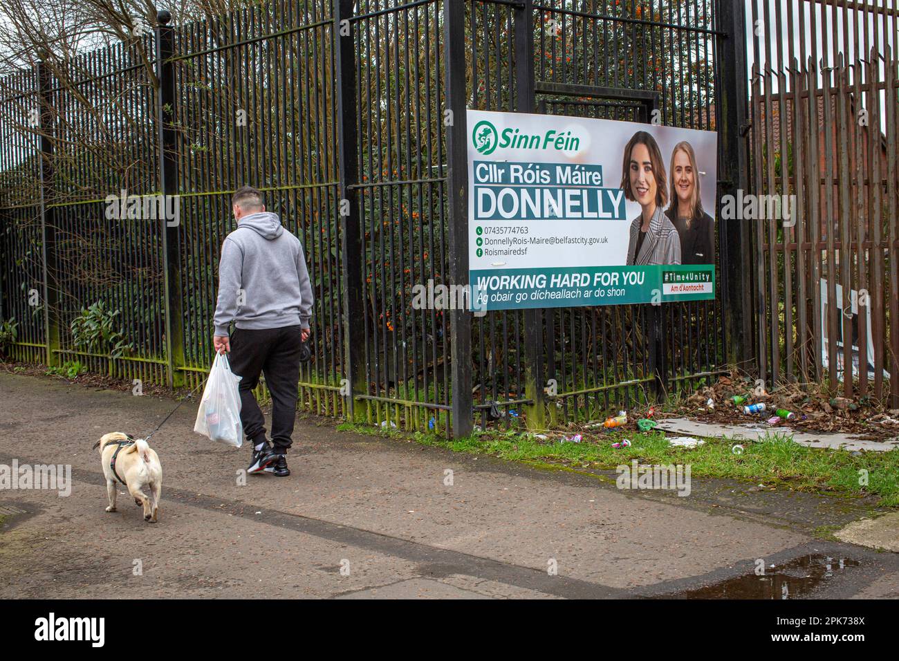 Ein Mann geht an einem Wahlplakat vorbei , auf dem Sinn Fein Councillor Róis-Máire Donnelly in West Belfast , Nordirland zu sehen ist . Stockfoto