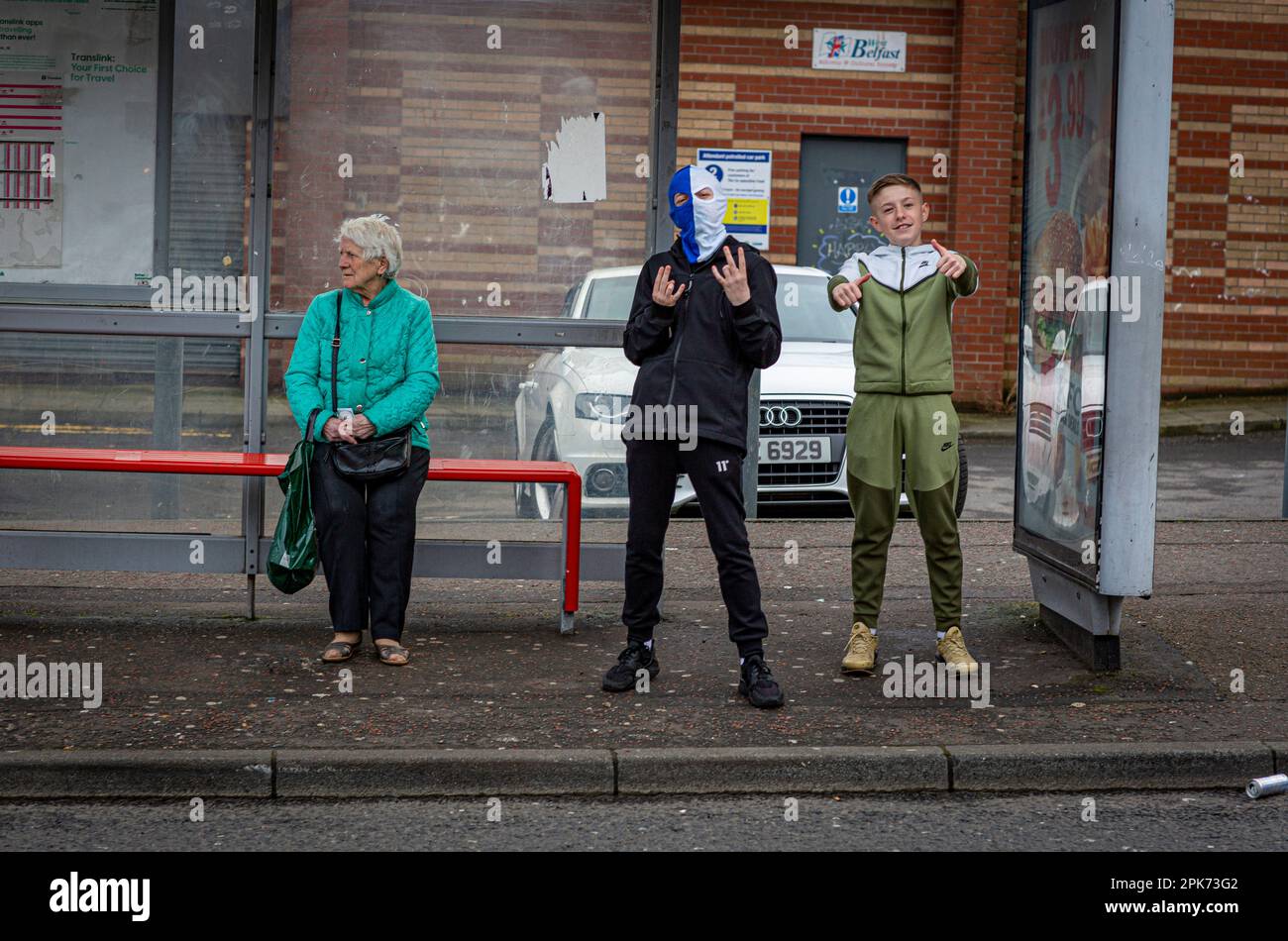 Ein Junge trägt eine Balaklava, um sein Gesicht an einer Bushaltestelle in Shankill Road, Belfast, County Antrim, Nordirland, Großbritannien, zu verstecken. Stockfoto