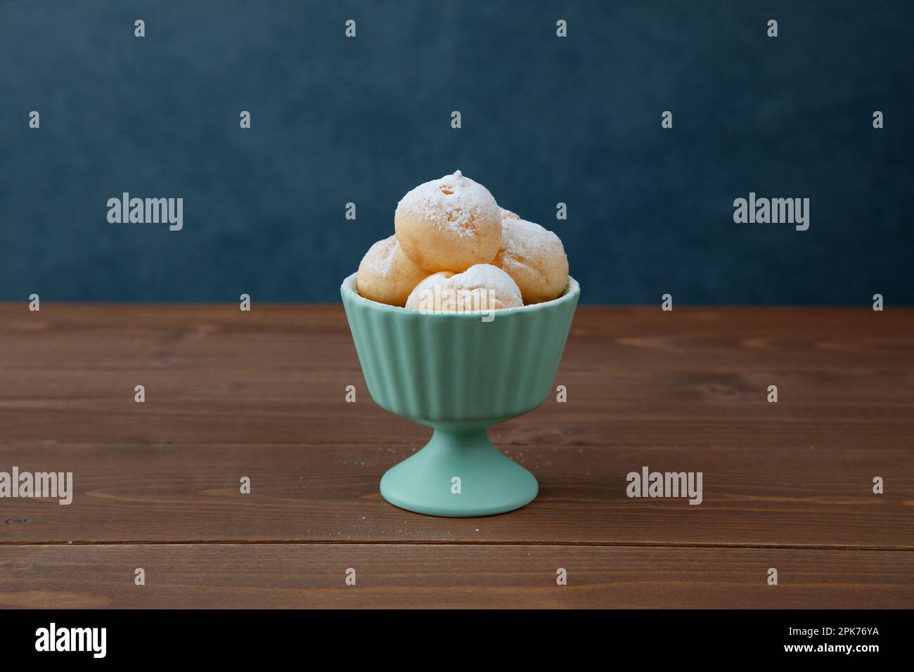 Creme-Puffs im Becher isoliert auf Holztisch Stockfoto