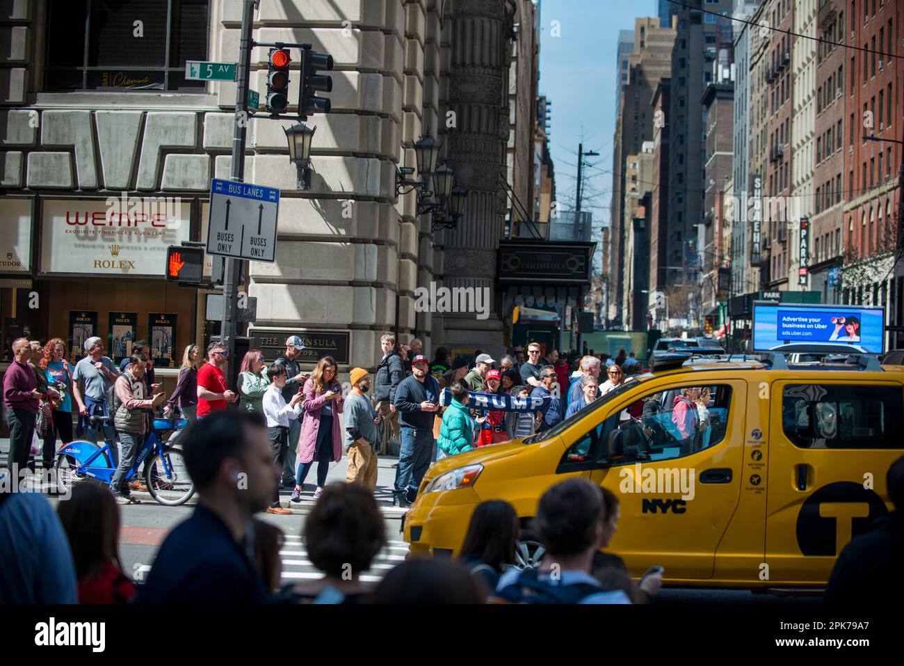 New York City Yellow Taxi fährt von Trump-Anhängern mit einem Trump-Schild entlang der belebten 55. St und 5. Ave NYC, am Morgen der Trump-Anklage. 04. April 2023 Stockfoto