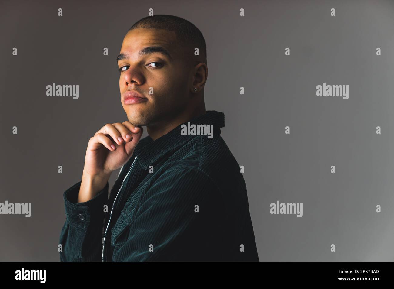 Junger afroamerikanischer Mann mit Buzz-Schnitt auf grauem, dunklem Studiohintergrund. Hochwertiges Foto Stockfoto