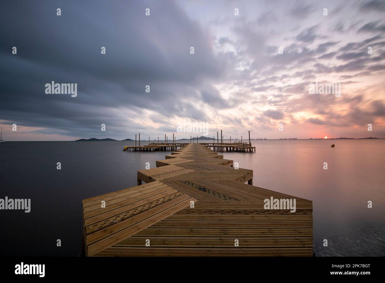 Holzsteg am Strand von Carmol im Mar Menor, bei einem bewölkten Sonnenaufgang, in Cartagena, Region Murcia, Spanien Stockfoto