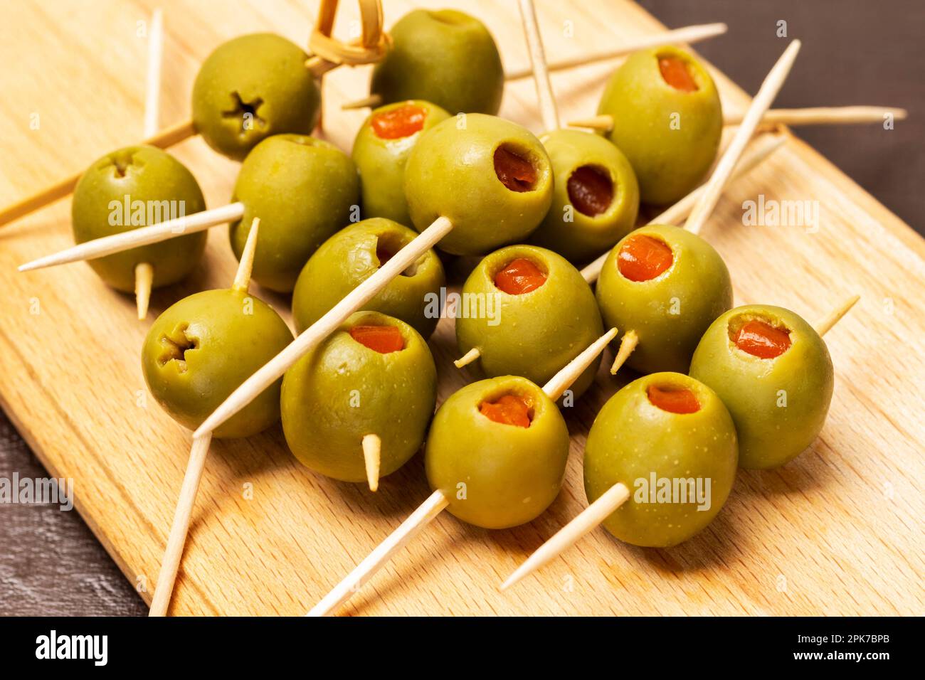 Oliven gefüllt mit Lachs auf Spießen. Schließen. Brauner Hintergrund. Stockfoto