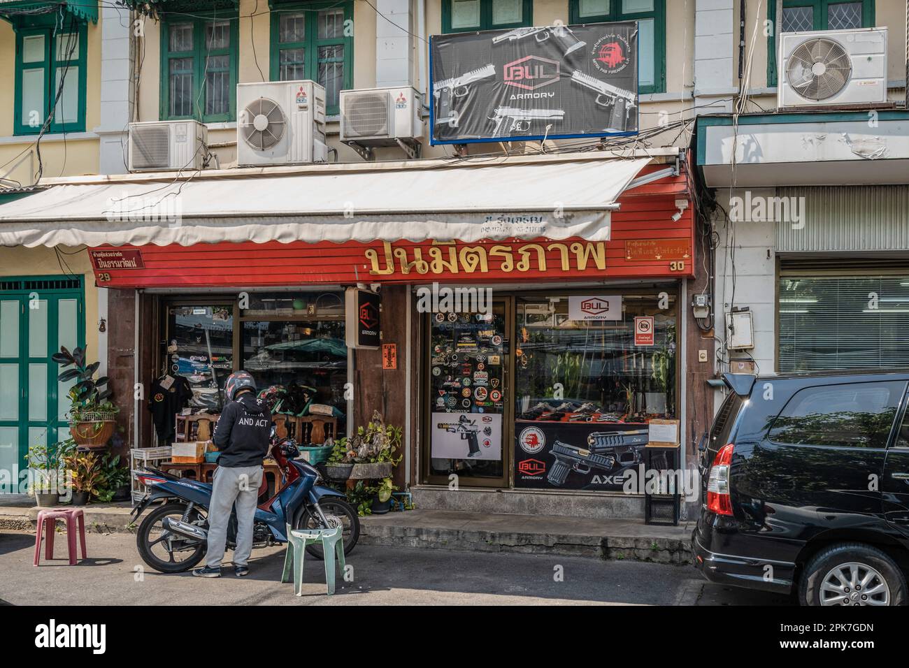 Bangkok, Thailand. 05. April 2023. Ein Kurier, der eine Jacke mit der Aufschrift „and Act“ trägt, steht vor einem Schusswaffen-, Munition- und Zubehörladen in der Long Tha Road, auch bekannt als Waffenmarkt, in Bangkok. Thailand ist weithin bekannt als einladendes Reiseziel und auch ein Land, das mit leicht zugänglichen Feuerwaffen überschwemmt ist. Es verfügt über die höchste Anzahl an Waffen in zivilen Händen in Südostasien und die höchste Mordrate mit Waffen in Asien. Der Markt für graue und schwarze Waffen ist blühend. (Foto: Nathalie Jamois/SOPA Images/Sipa USA) Guthaben: SIPA USA/Alamy Live News Stockfoto