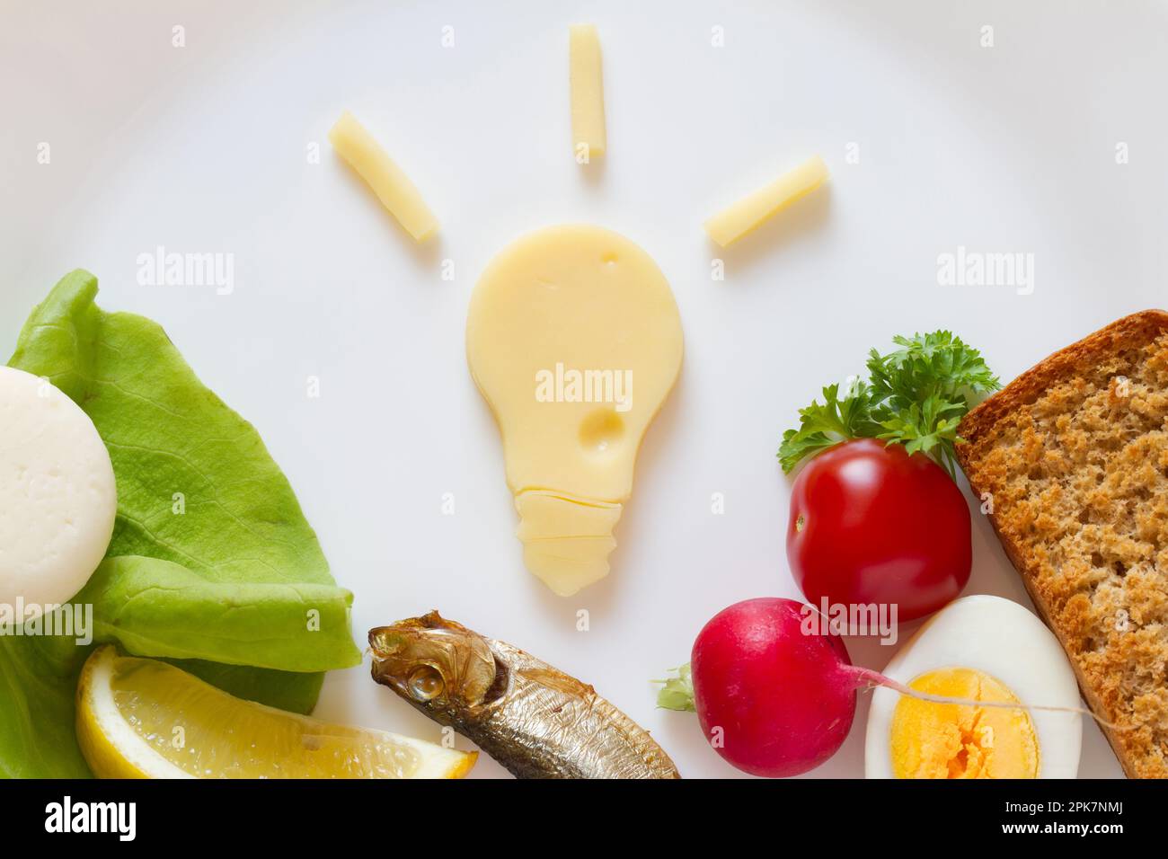 Eine Idee zur Inspiration für Speisen, eine Glühbirne aus Käse und Lebensmittelprodukte auf dem Teller Stockfoto
