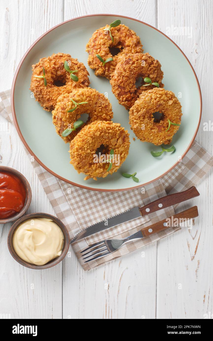 Donug ist ein großer Chicken Nugget, der in einen Kreis geformt ist, sodass er wie ein Donut auf dem Teller auf dem Tisch aussieht. Vertikale Draufsicht von einem Stockfoto