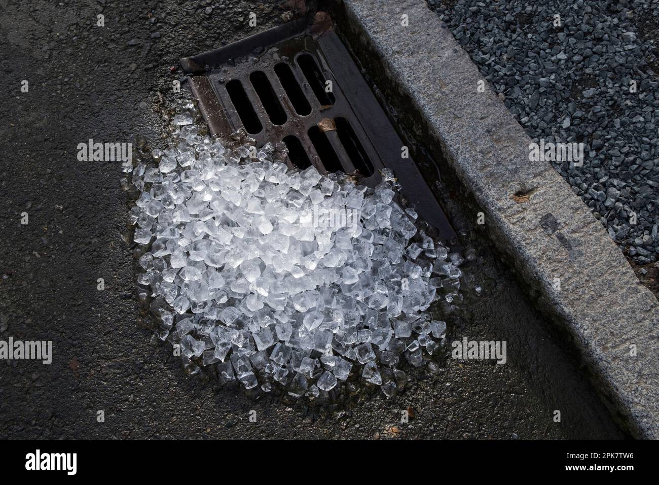 Ein Haufen Schmelzeis, weggeworfenes Eis durch einen Abfluss auf einer Straße. Stockfoto
