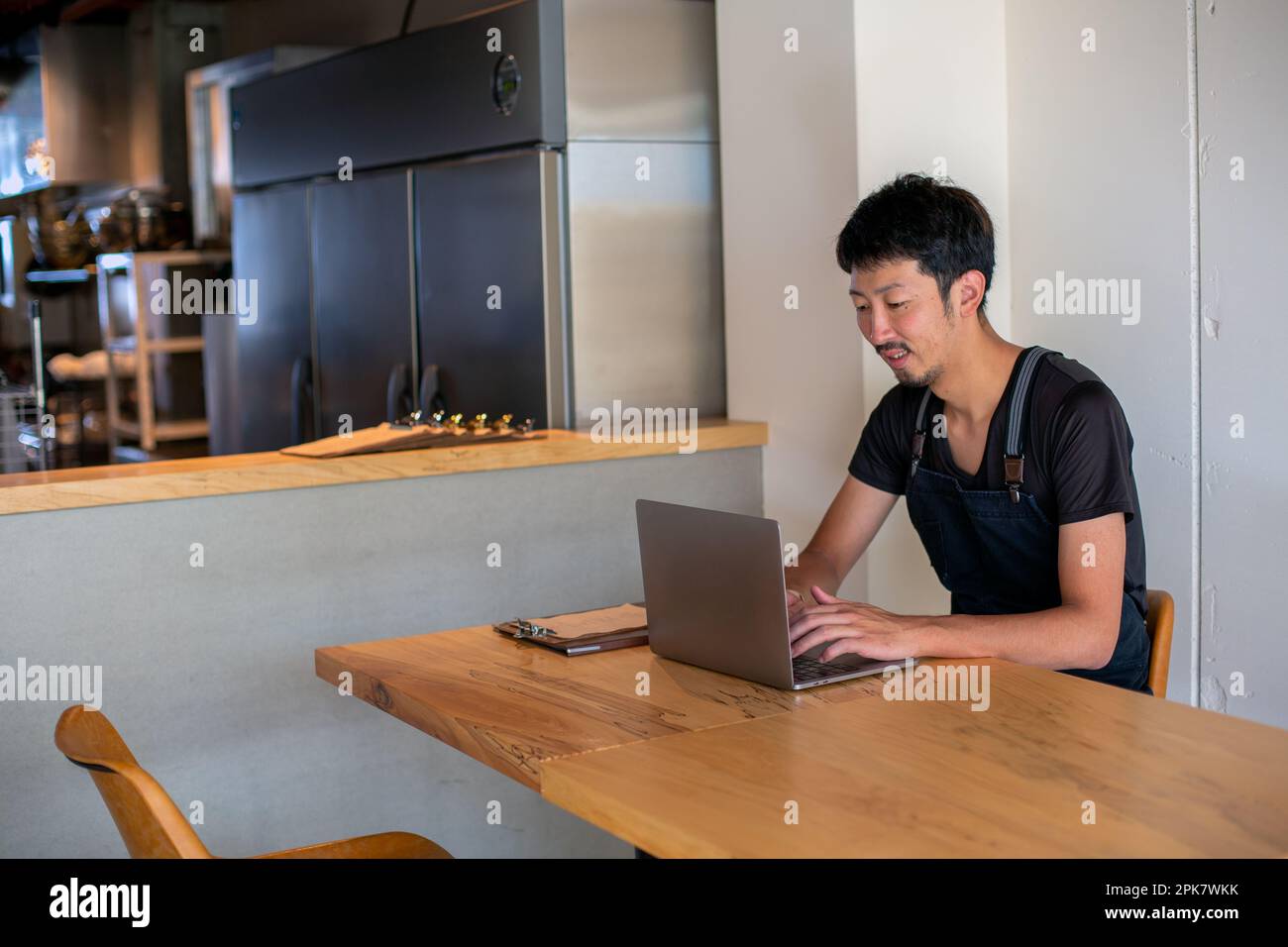Ein Mann, der mit einem Laptop an einem Tisch saß, Besitzer und Manager eines kleinen Restaurants. Stockfoto