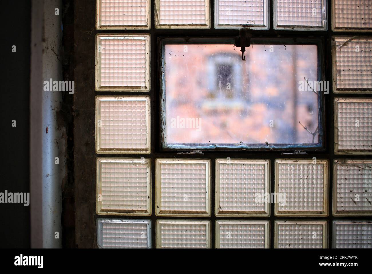 Nahaufnahme eines trostlosen und schmutzigen Fabrikfensters aus Glasziegeln. Stockfoto