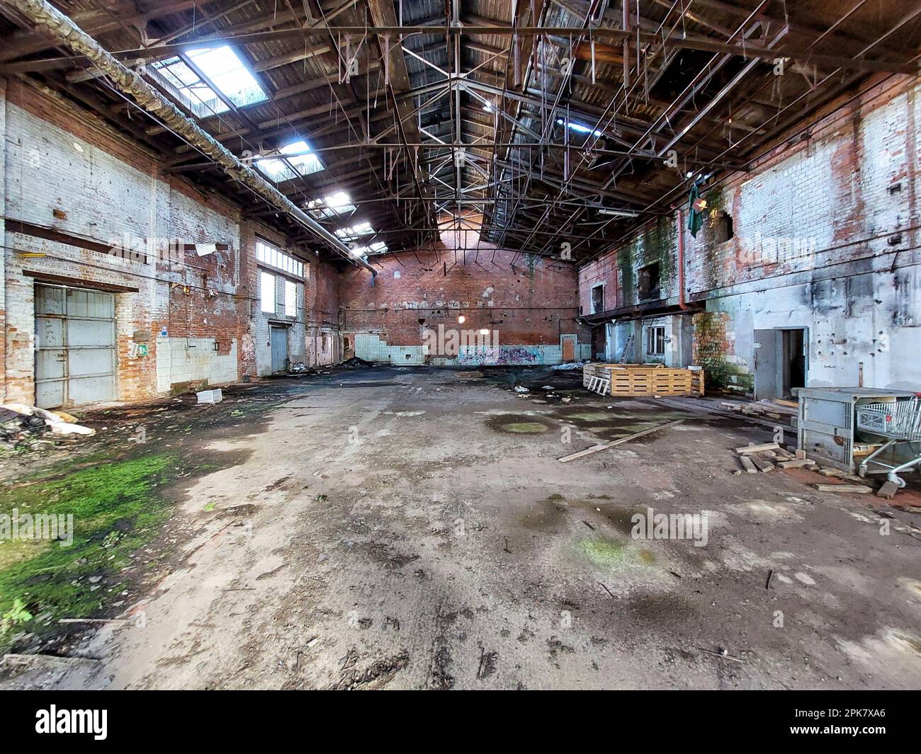 Zentrale Perspektive einer zerstörten Fabrikhalle mit Trümmern. Stockfoto
