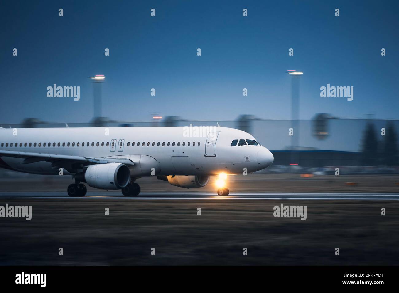 Gewerbliche Flugzeuge während des Starts auf der Start- und Landebahn des Flughafens bei Nacht. Ebene in unscharfer Bewegung. Stockfoto