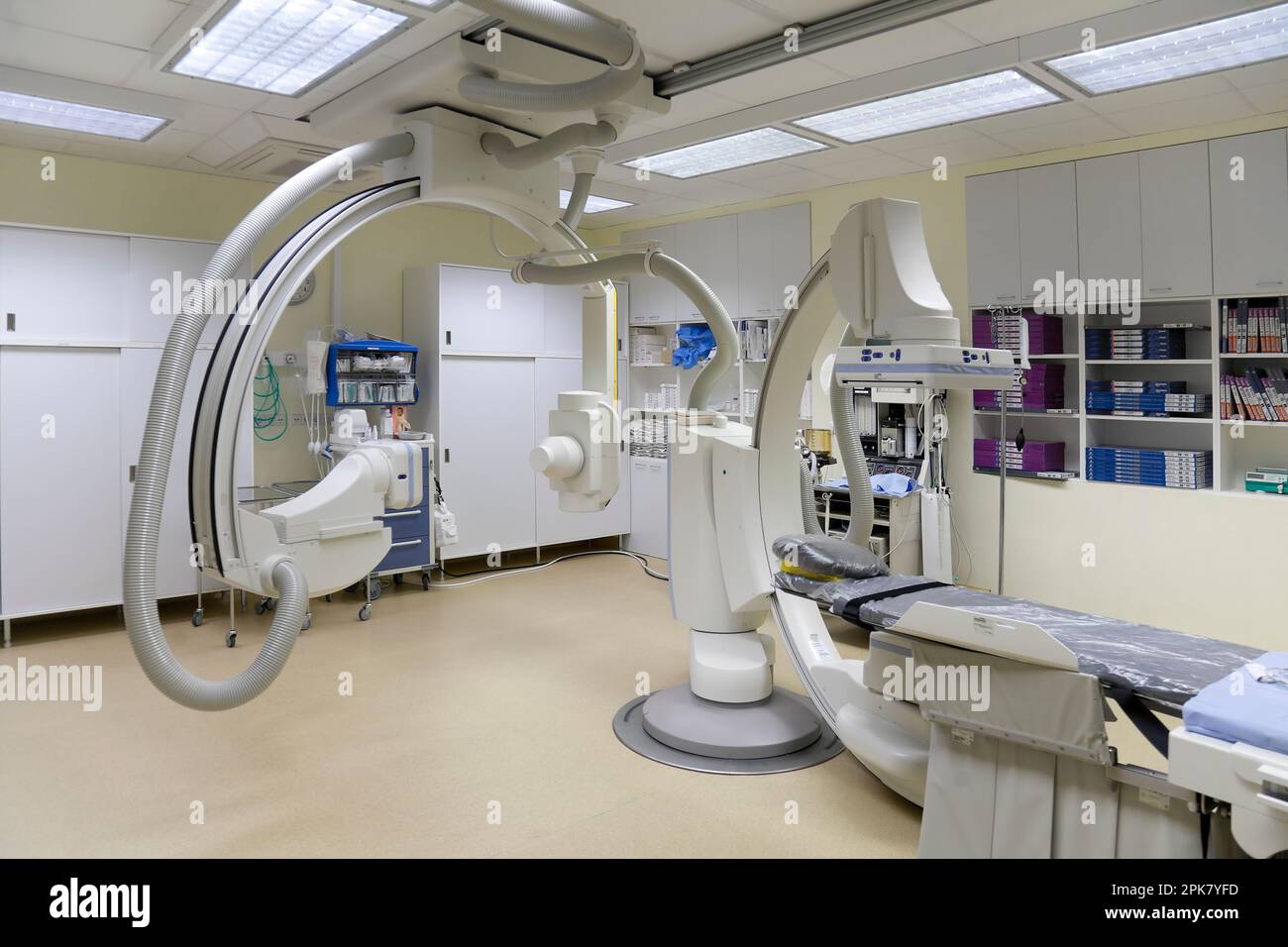 Ein modernes Krankenhauszimmer, ein großes tragbares mobiles Scangerät mit gebogenen Armen, ein mobiler Scanner und eine Krankenwagen oder ein Bett. Stockfoto