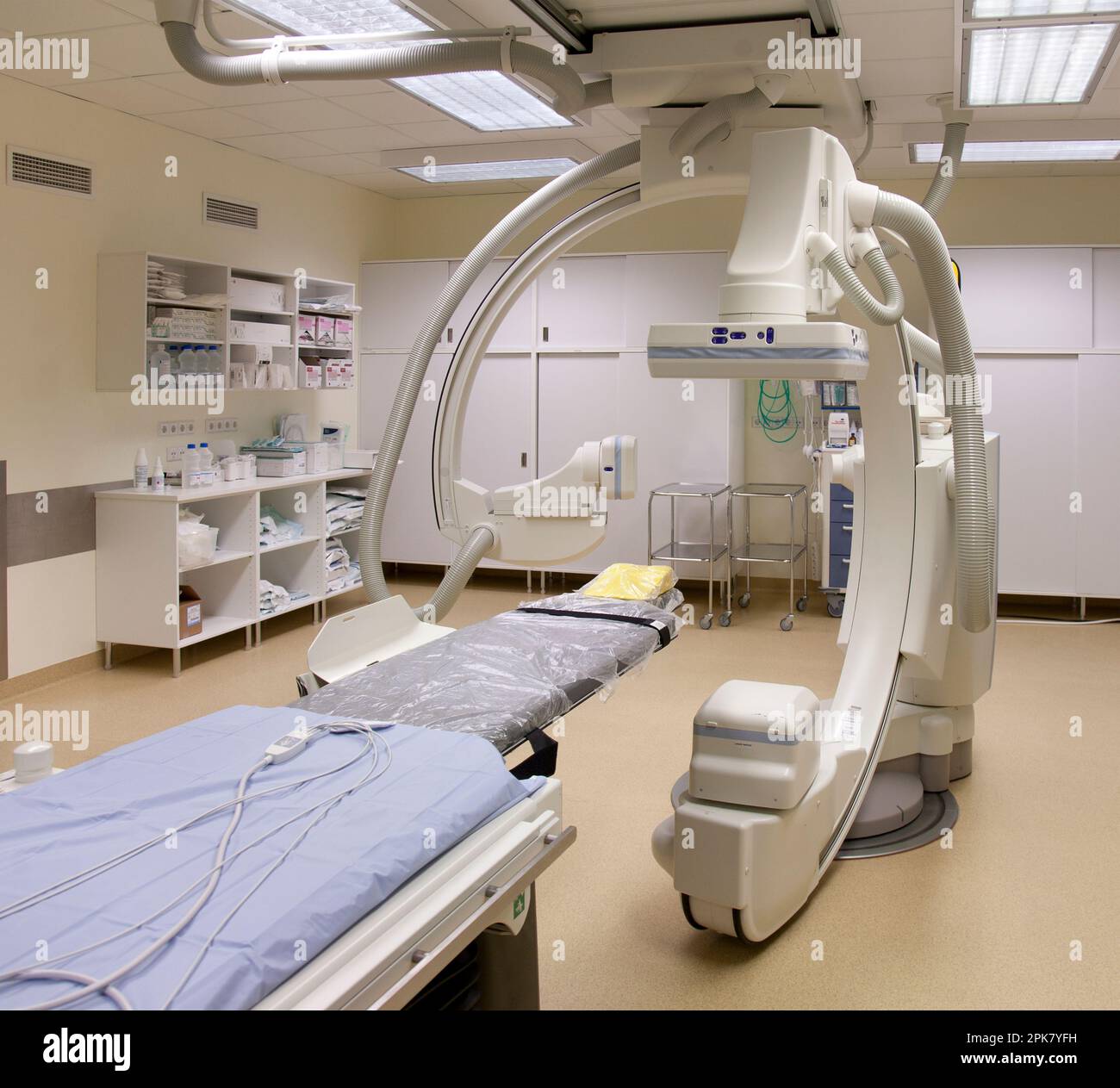 Ein modernes Krankenhauszimmer, ein großes tragbares mobiles Scangerät mit gebogenen Armen, ein mobiler Scanner und eine Krankenwagen oder ein Bett. Stockfoto