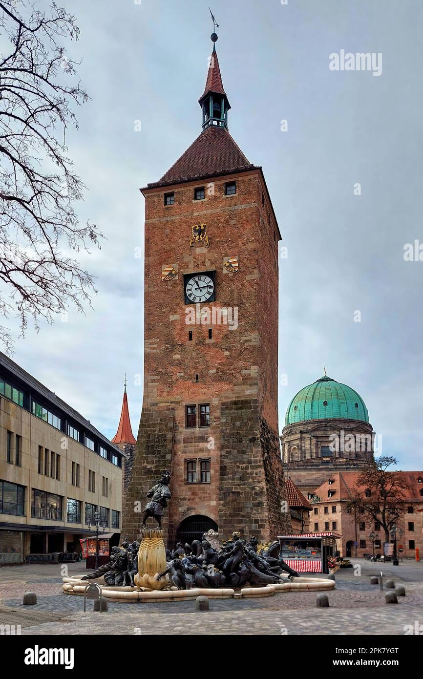 Platz in der Mitte von Nürnberg mit dem Weißen Turm (beleuchteter weißer Turm) und dem Ehekarussel-Brunnen von Hans Sachs. Stockfoto