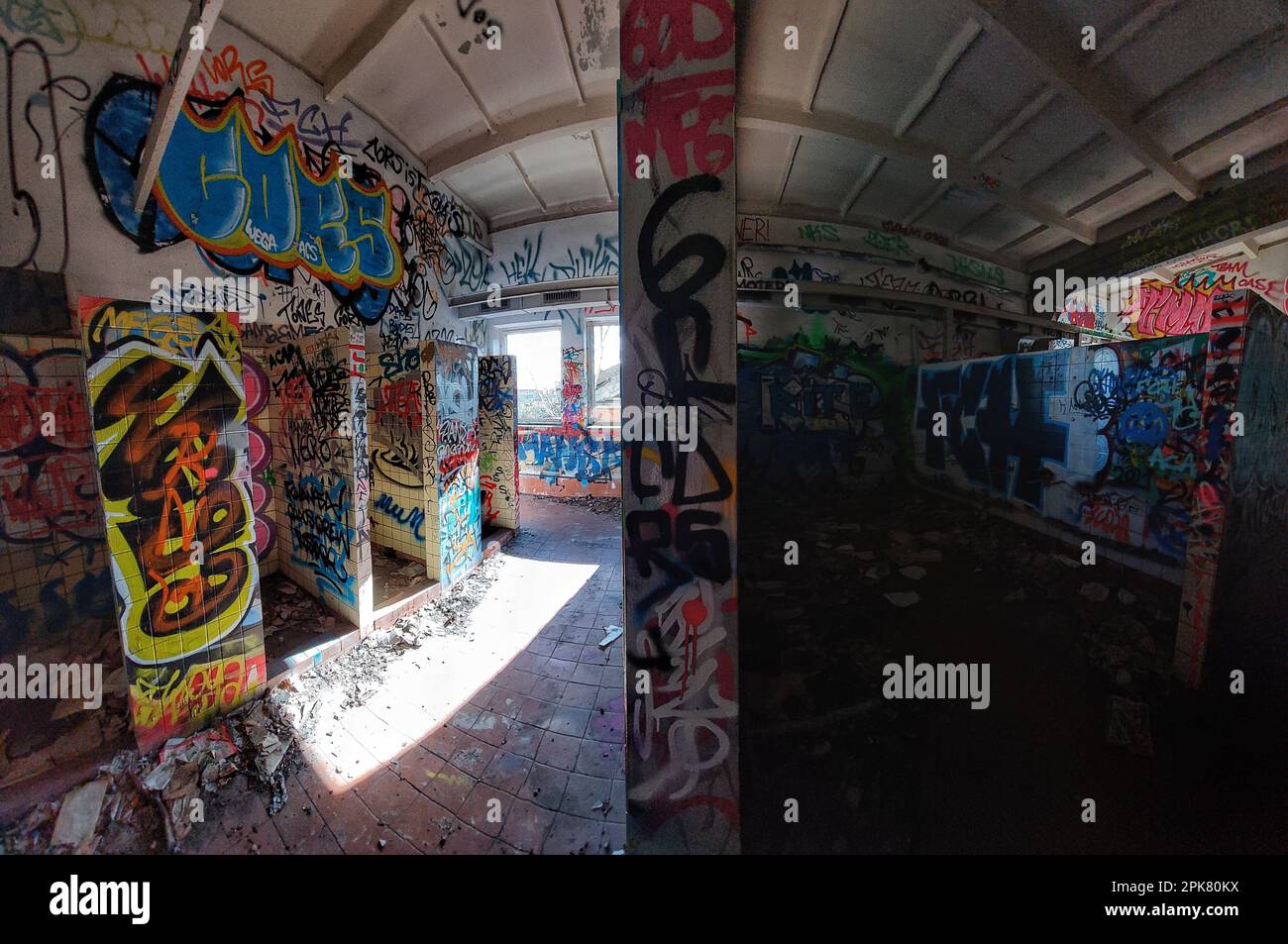 Verlassene Badezimmer mit Trennwand, die einen hellen und dunklen Bereich schafft. Stockfoto