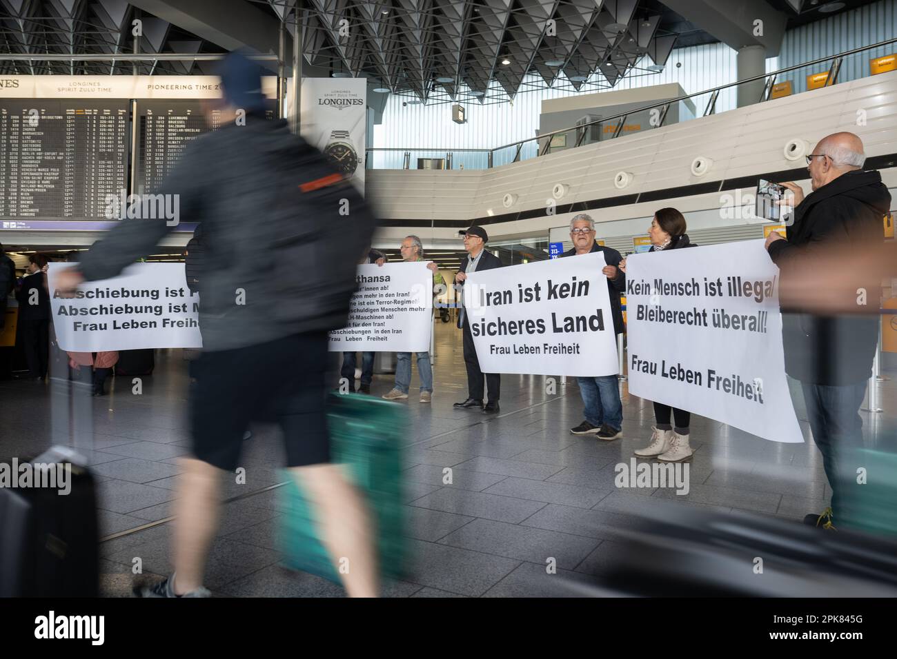 Frankfurt, Deutschland. 06. April 2023 Während einer Demonstration am Frankfurter Flughafen gegen die Beteiligung der Fluggesellschaft an Abschiebungsflügen in den Iran gehen Reisende vor den Schaltern der Lufthansa an Demonstranten vorbei. Zuletzt gab es zwei Flüge mit deportierten Menschen in den Iran. Foto: Sebastian Gollnow/dpa/Alamy Live News Stockfoto