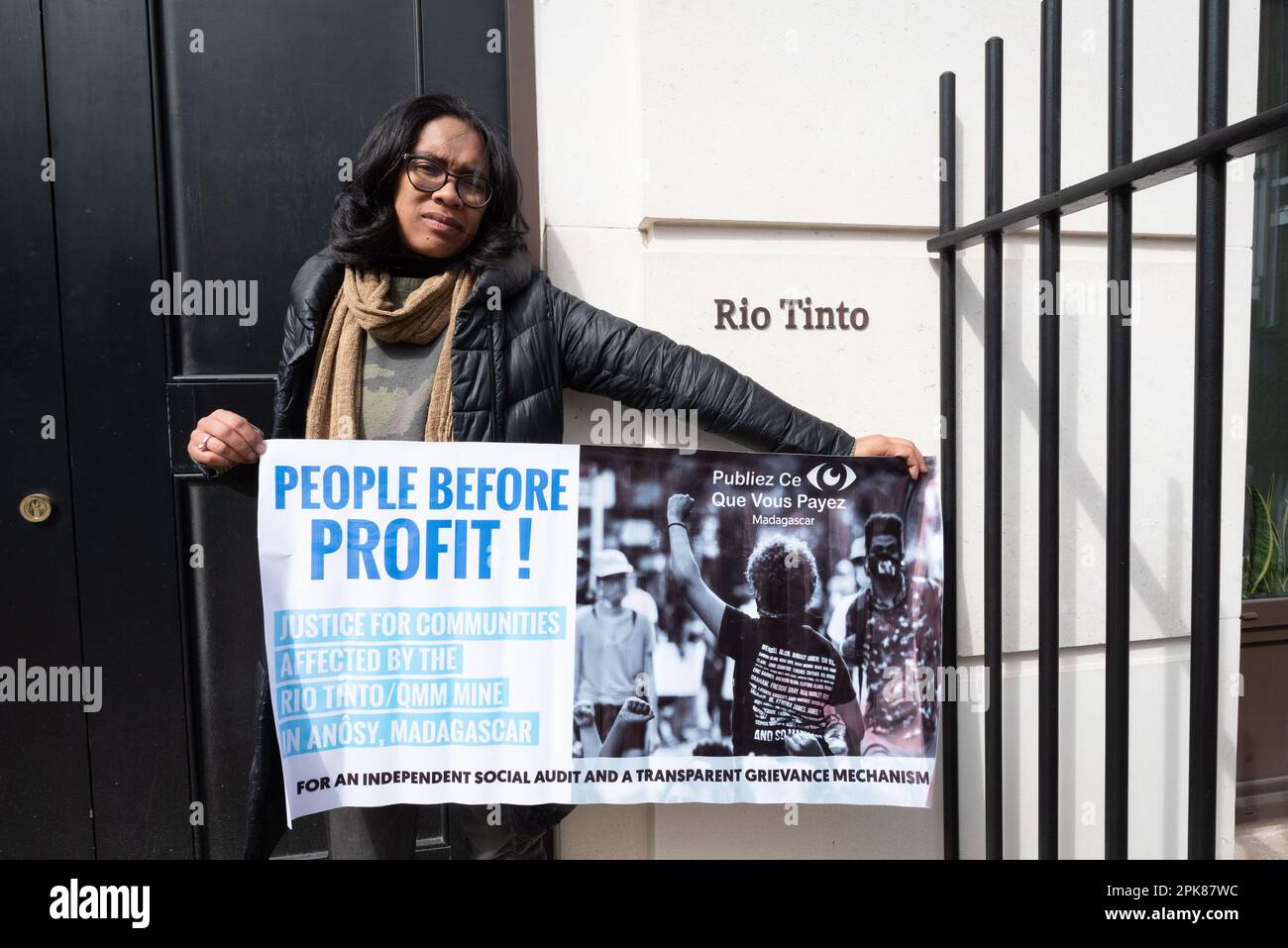 London, Großbritannien. 5. April 2023 Ein Aktivist des London Mining Network hält bei einem Protest außerhalb des britischen Hauptsitzes von Rio Tinto ein Banner mit dem Titel „Menschen vor dem Profit“. Stockfoto
