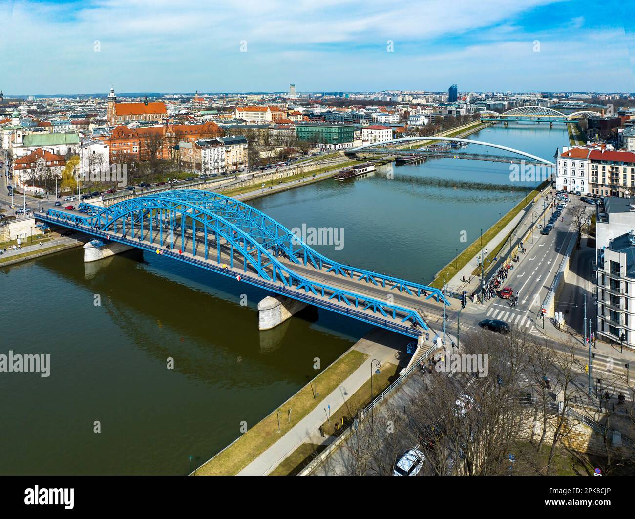 Brücken auf der Weichsel in Krakau, Polen. Luftaufnahme. Boulevards mit weckenden Leuten. Blaue Bogenbrücke vorne. Fußgängerbrücke für Fußgänger und Stockfoto