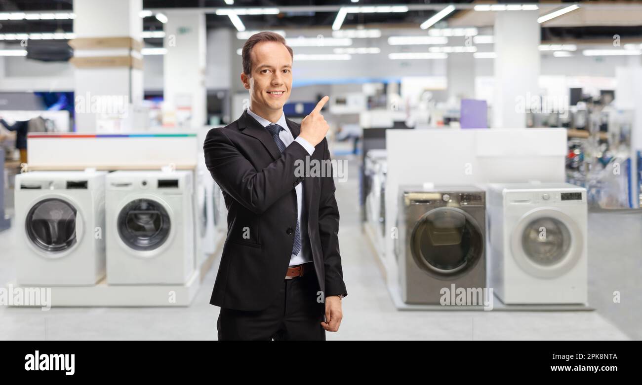 Ein Geschäftsmann, der auf einen Haushaltswarenladen mit Waschmaschinen zeigt Stockfoto