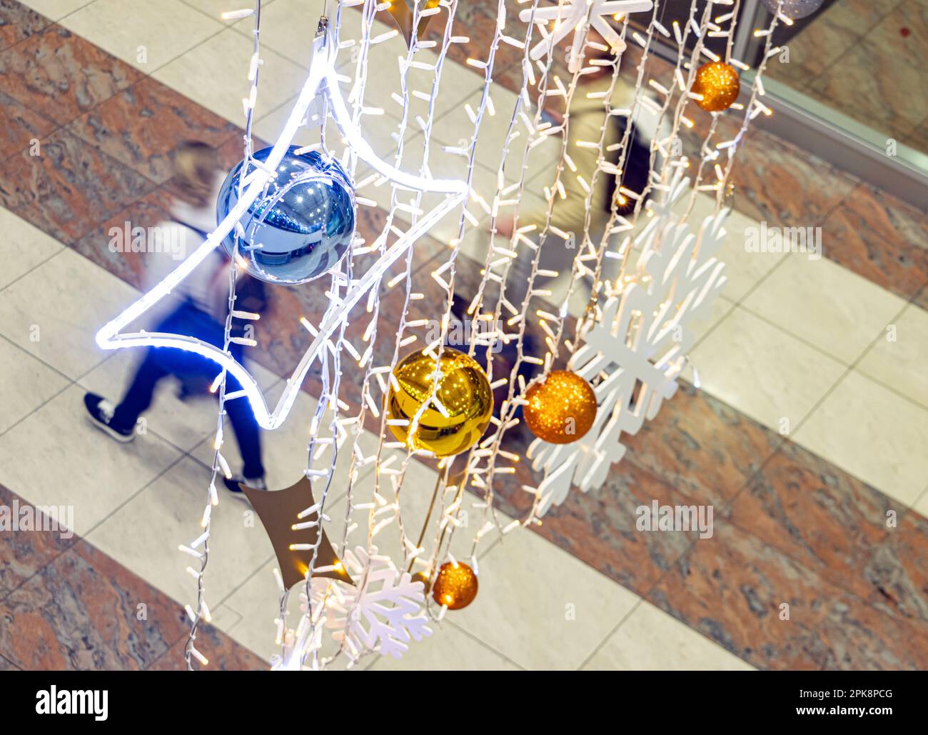 Die Leute laufen unter der Weihnachtsdekoration, die in der Flughafenhalle hängt Stockfoto