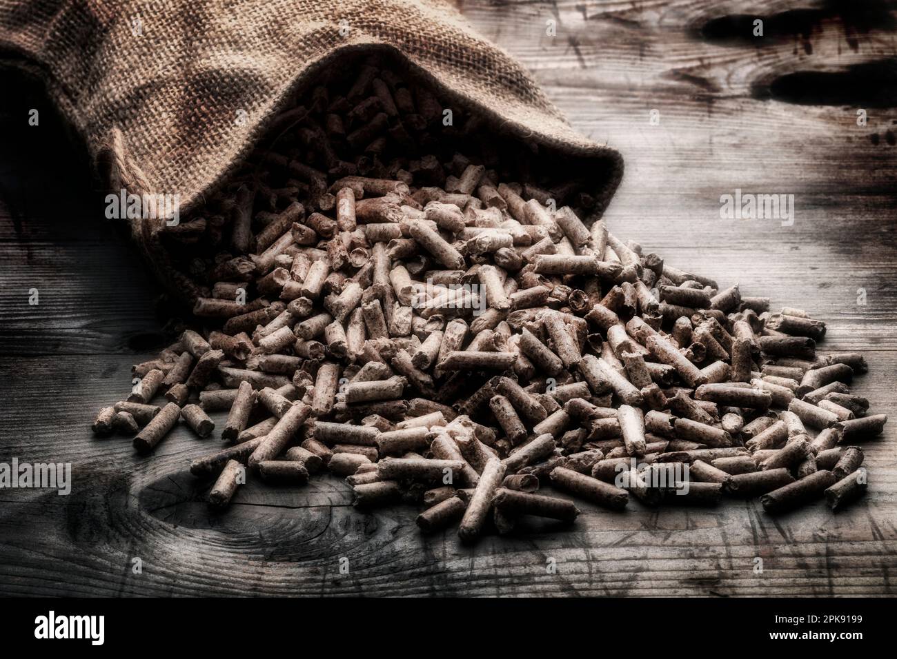 Holzpellets mit Jutesack auf rustikalem Holzhintergrund Stockfoto