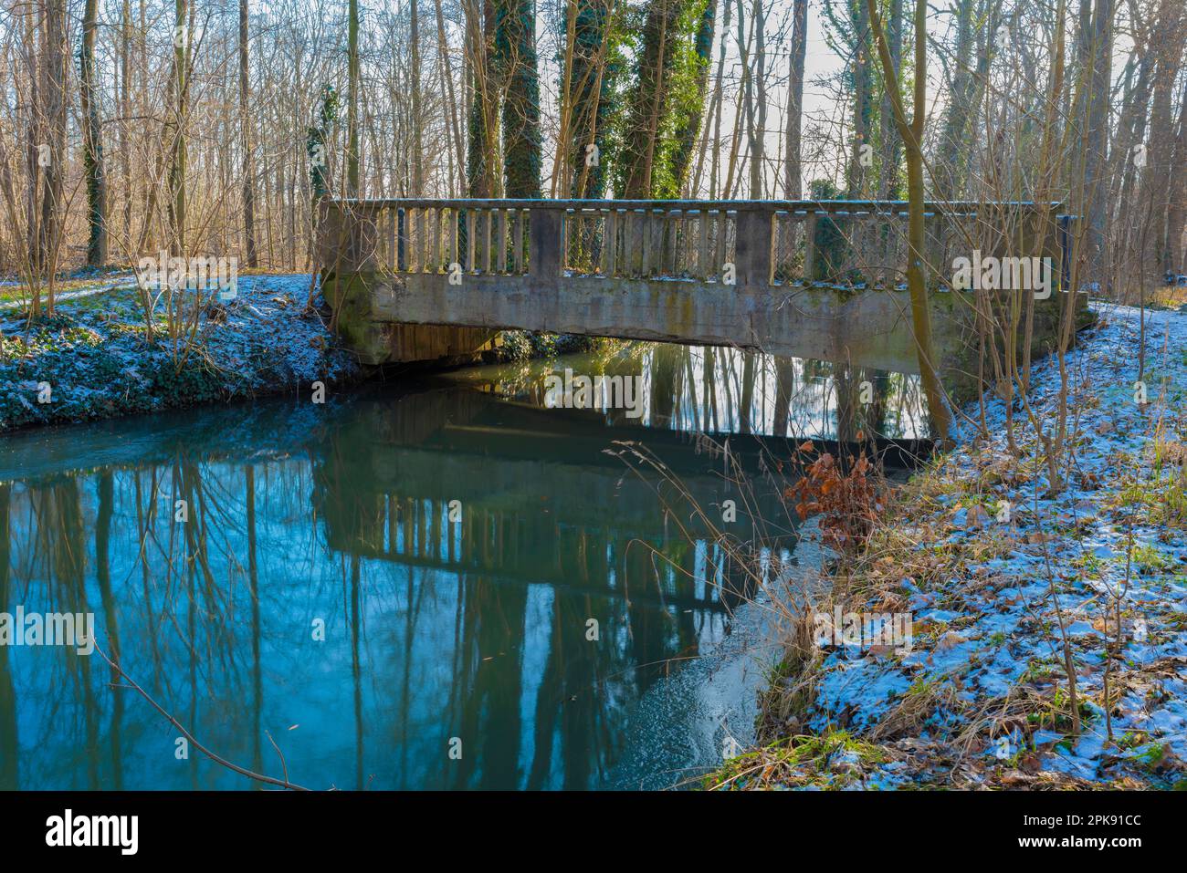 Kleiner Fluss im Wald im Winter mit sehr alter Betonbrücke Stockfoto