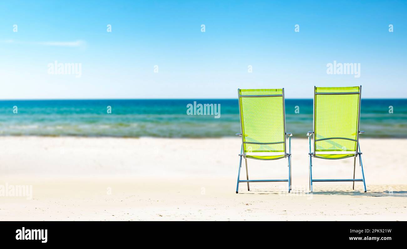 Zwei Sonnenliegen am Strand vor dem blauen Meer [M] Stockfoto