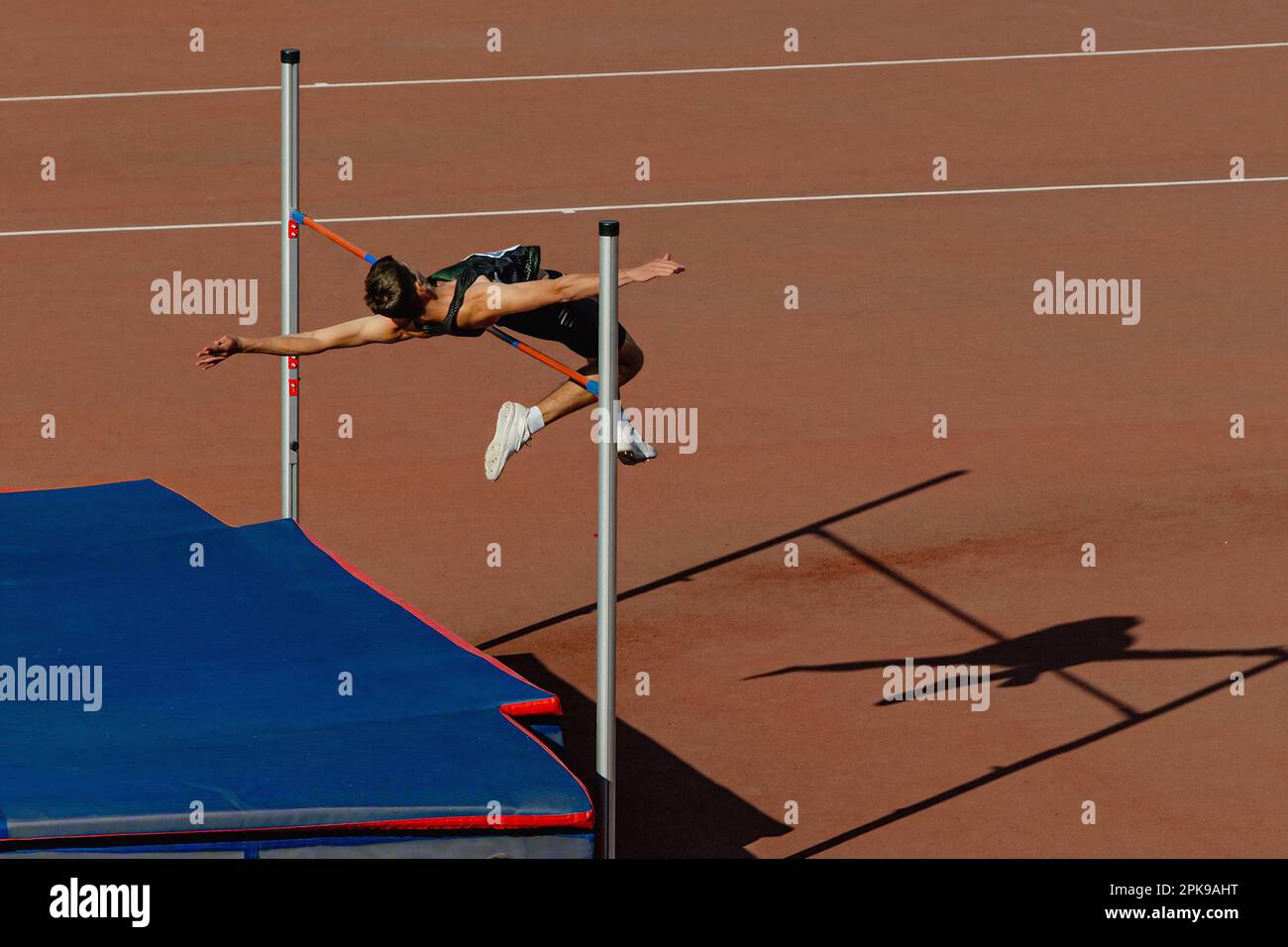 Athleten-Jumper-High-Jump im Sommer-Sport-Wettkampf, Silhouette-High-Jumper auf rotem Track-Stadion Stockfoto