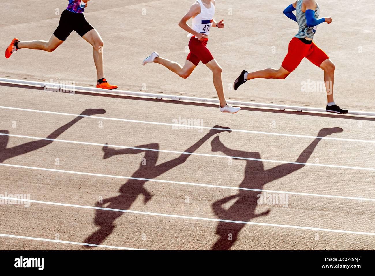 Drei Läufer sind Mittelstreckenläufer im Sommer-Sportwettbewerb, ein Silhouette-Jogger auf rotem Track Stadium Stockfoto