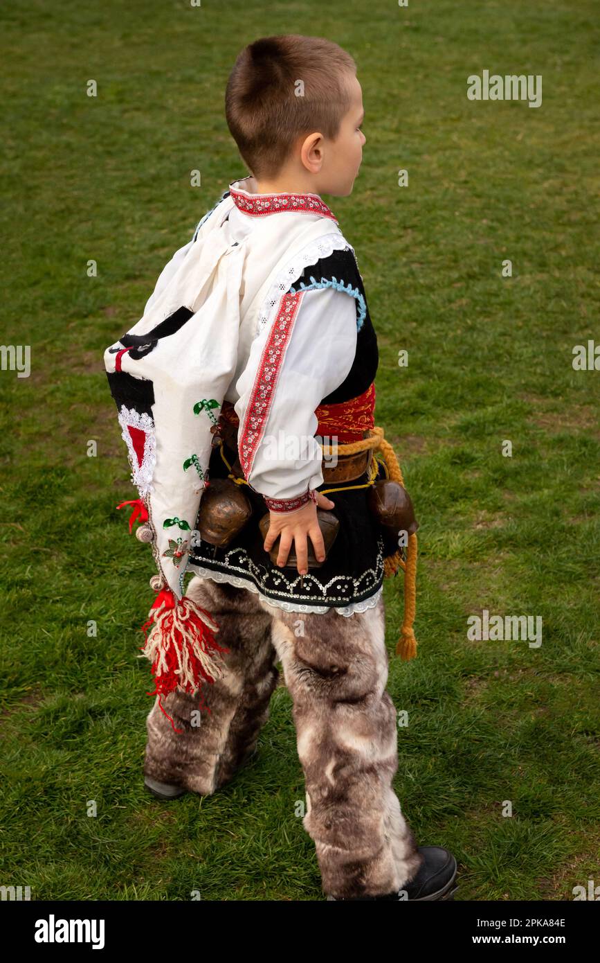 Der kleine Junge entlarvte Kukeri Tänzer mit kompliziertem Kostüm nach seinem Auftritt beim jährlichen Simitlia Festival in Simitli, Bulgarien, Osteuropa Stockfoto