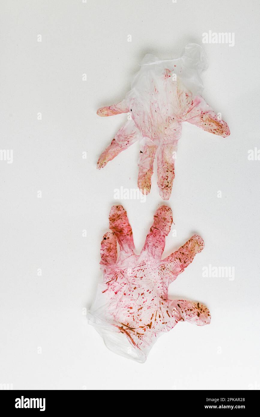 Rot verfärbtes Paar Einweghandschuhe auf einer weißen Oberfläche Stockfoto