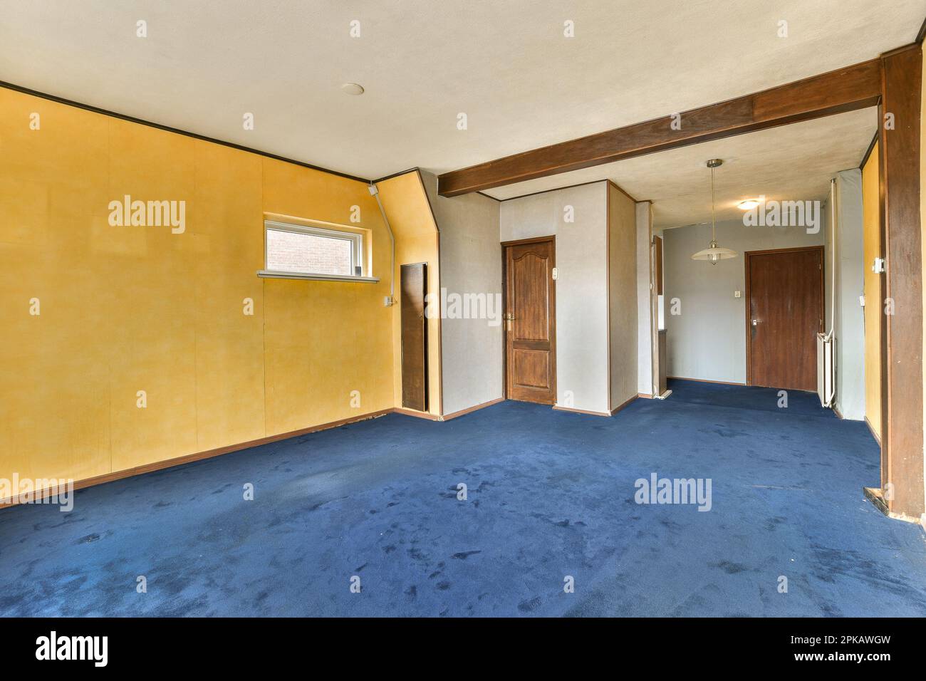 Ein leerer Raum mit gelben Wänden und blauem Teppichboden, zwei Türen öffnen sich auf beiden Seiten zur anderen Seite Stockfoto