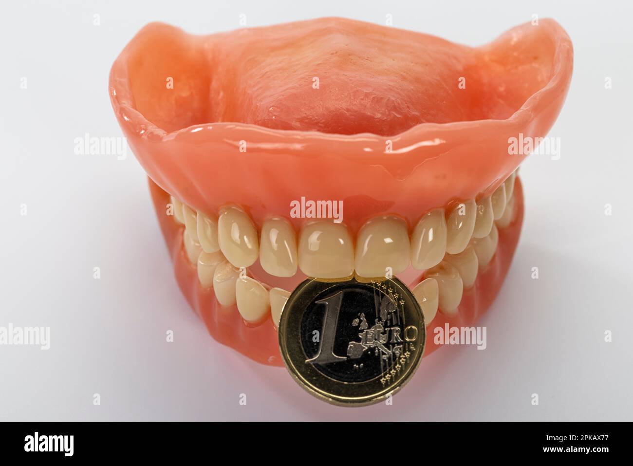 Zahnersatz mit einer 1-Euro-Münze, Symbolbild, Zahnersatz, Zuzahlung, weißer Hintergrund, Stockfoto