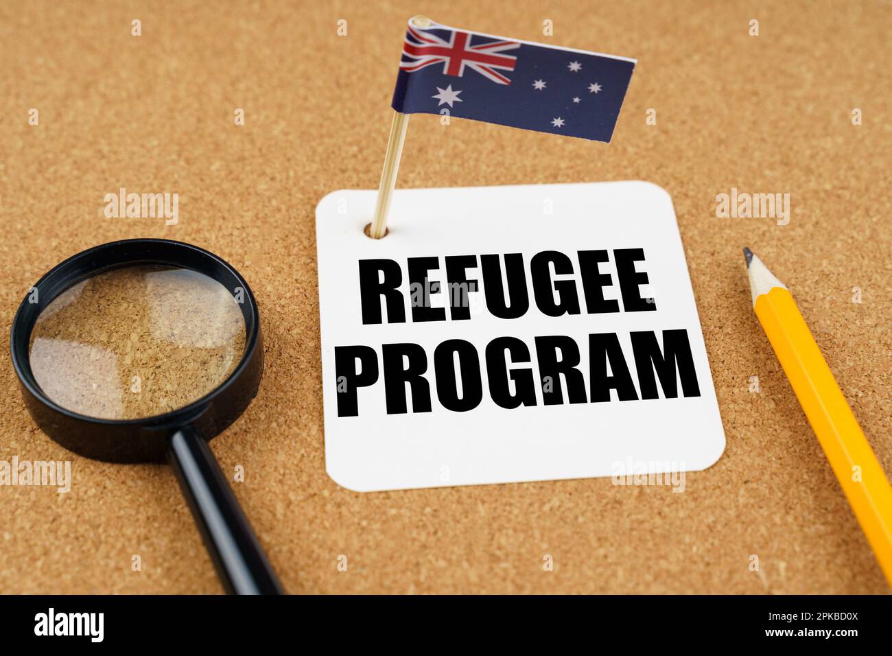 Auf dem Tisch liegt die Flagge Australiens, ein Bleistift, eine Lupe und ein Blatt Papier mit der Inschrift - Flüchtlingsprogramm Stockfoto