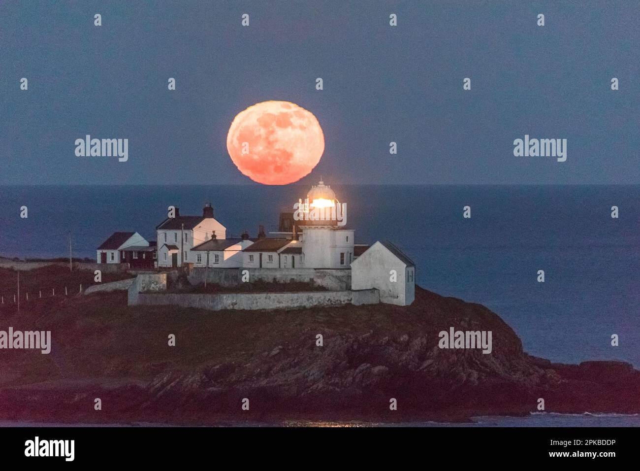 Roches Point, Cork, Irland. 06. April 2023. Hinter dem Leuchtturm von Roches Point, Co., erhebt sich ein rosa Mond Cork, Irland. David Creedon/Alamy Live News Stockfoto