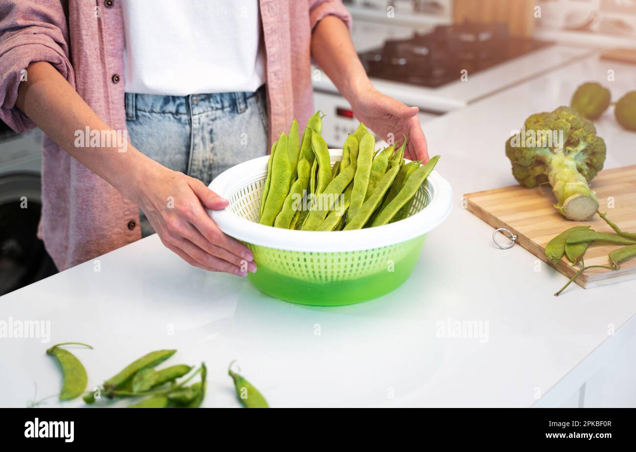 Ein Mädchen in einem rosa Hemd und einem weißen T-Shirt steht zu Hause in der Küche und wird eine vegetarische Diät kochen.Konzept einer gesunden Ernährung Stockfoto