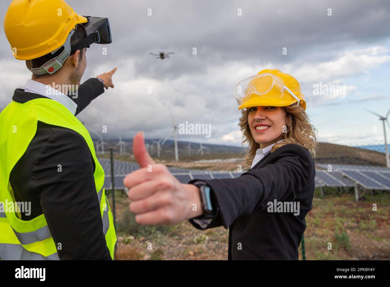 Zwei Ingenieure während einer Inspektion mit Drohne und VR-Headsets in einer Solarfarm, zufriedener Ausdruck. Stockfoto