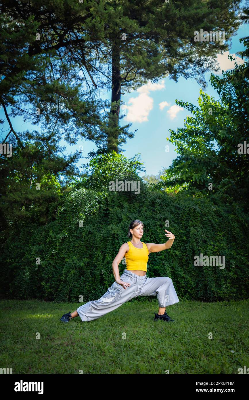 Eine Frau, die im Park Tai Chi Quan praktiziert. Tai Chi ist eine körperliche und geistige Praxis aus China, die sanfte, fließende Bewegungen mit verbindet Stockfoto