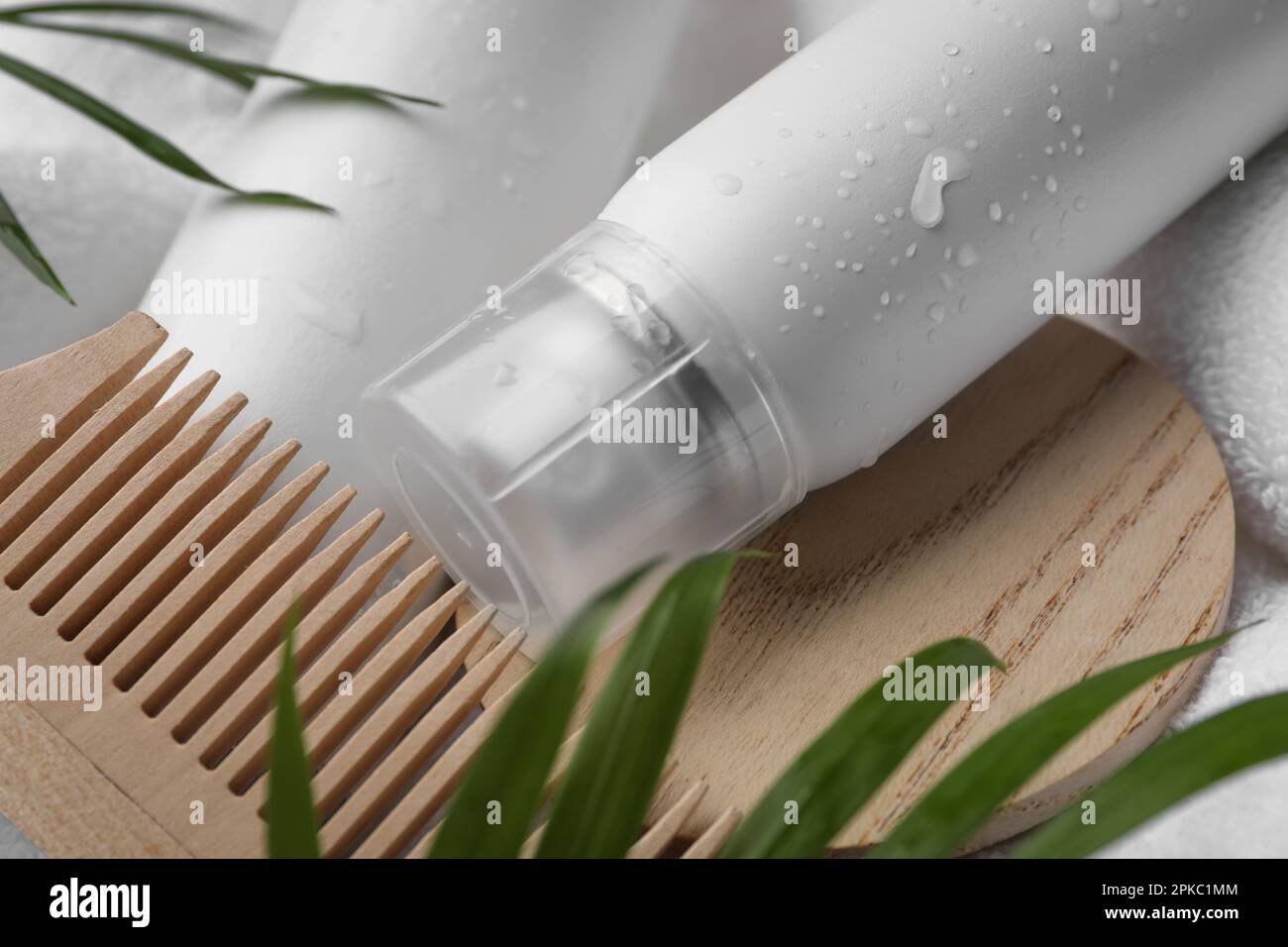 Nassflasche mit Shampoo-Spray und Holzkamm auf weißem Handtuch, Nahaufnahme Stockfoto