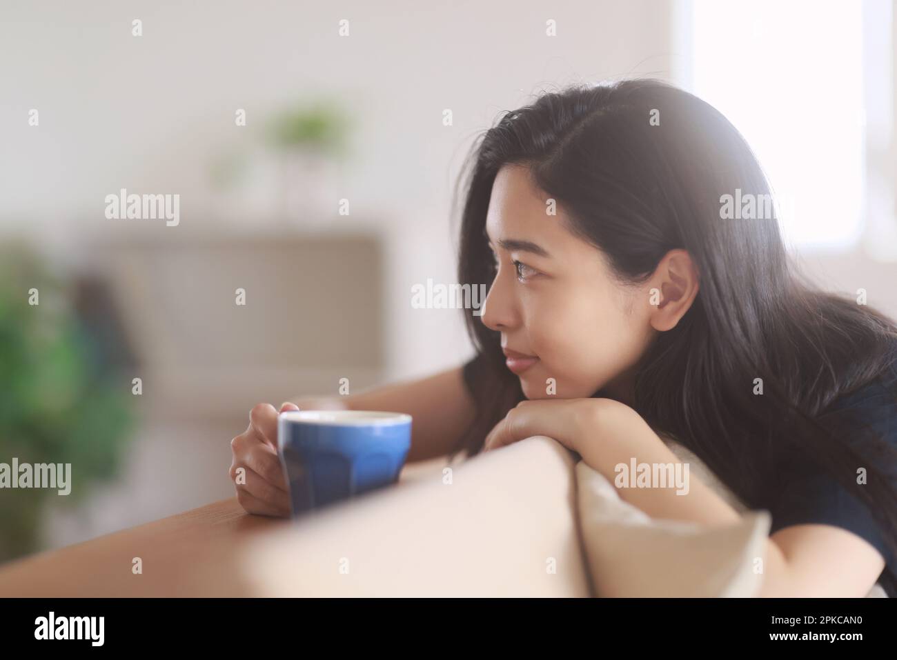 Frau trinkt Kaffee im Wohnzimmer Stockfoto