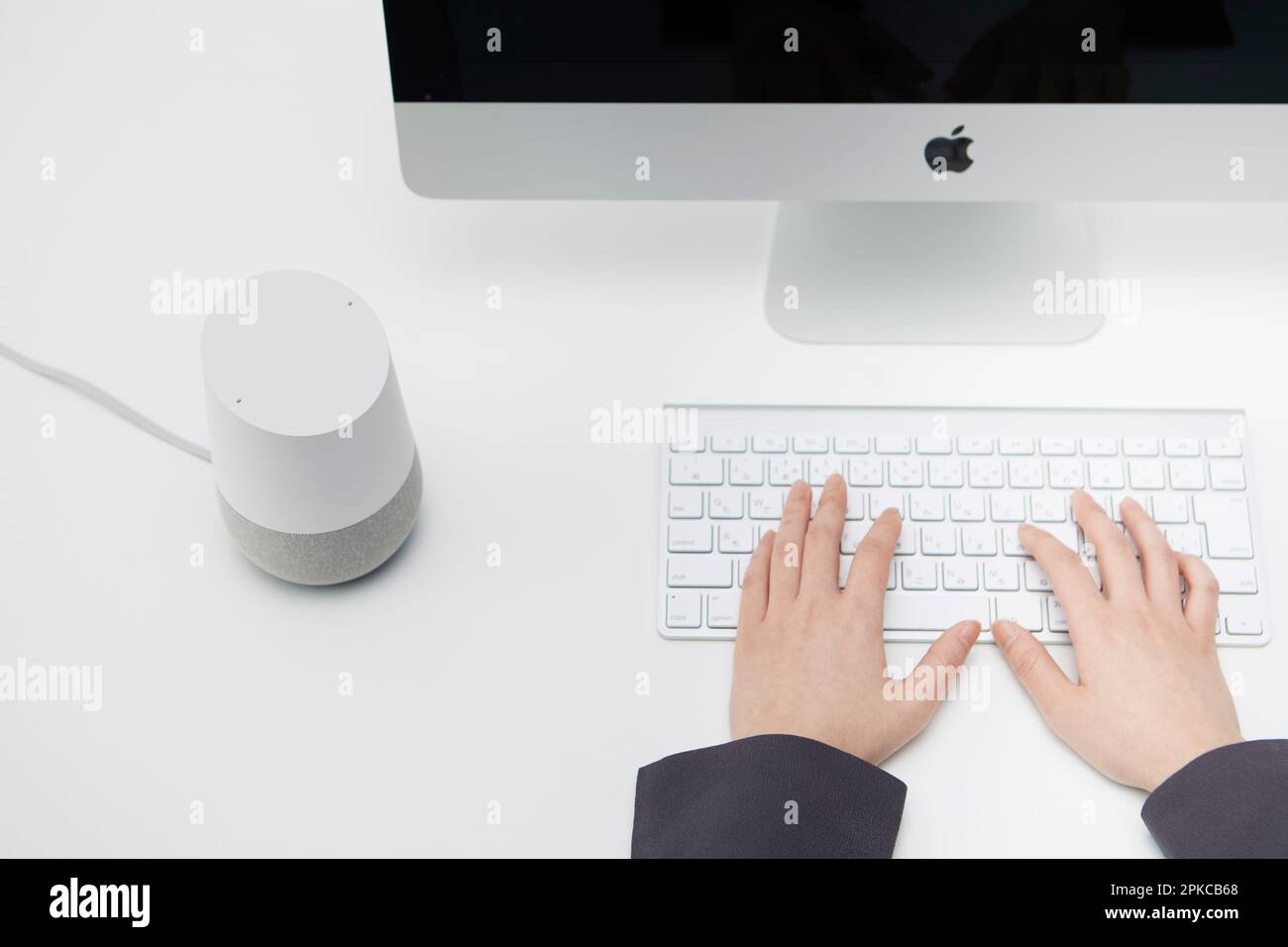 AI-Lautsprecher neben einem Computer auf einem weißen Schreibtisch Stockfoto