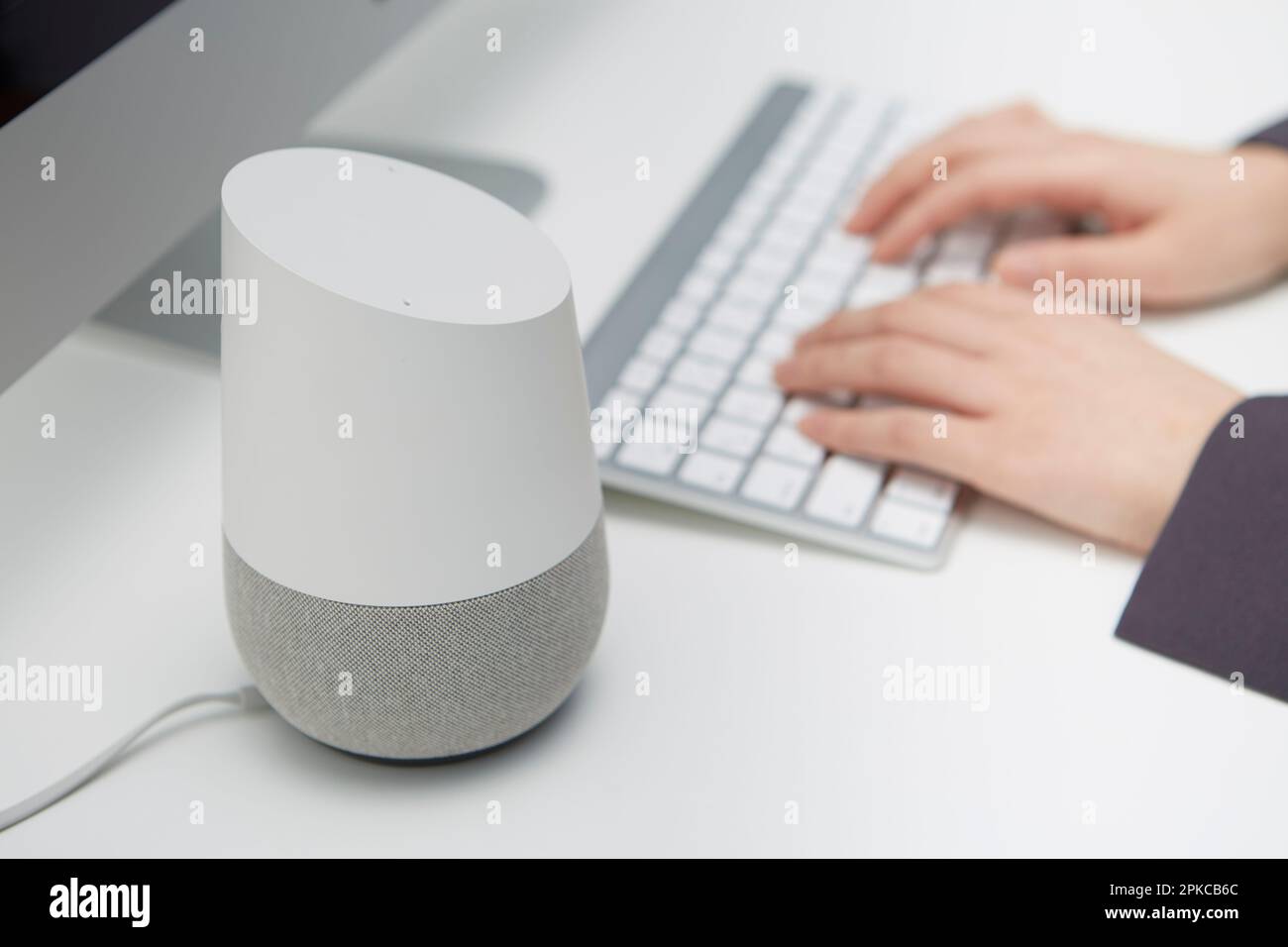 AI-Lautsprecher neben einem Computer auf einem weißen Schreibtisch Stockfoto