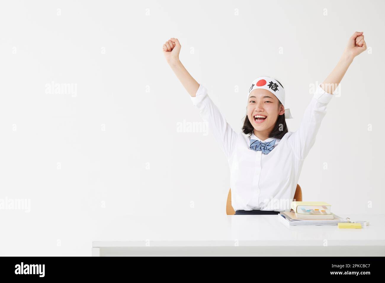 Ein Highschool-Mädchen hob ihre Arme, während sie ein Hachimaki trug Stockfoto