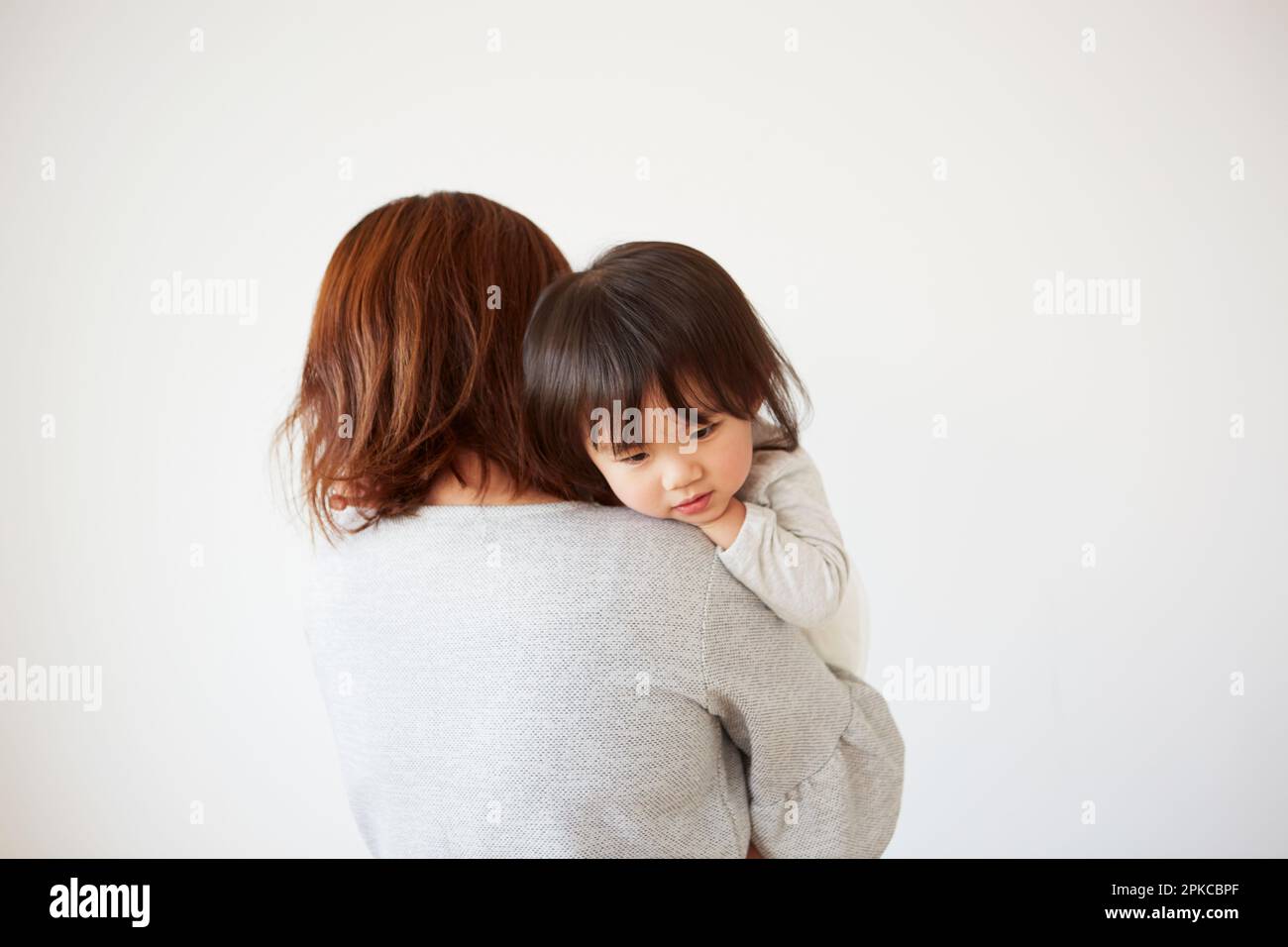 Das Baby liegt mit dem Gesicht nach unten in den Armen der Mutter Stockfoto