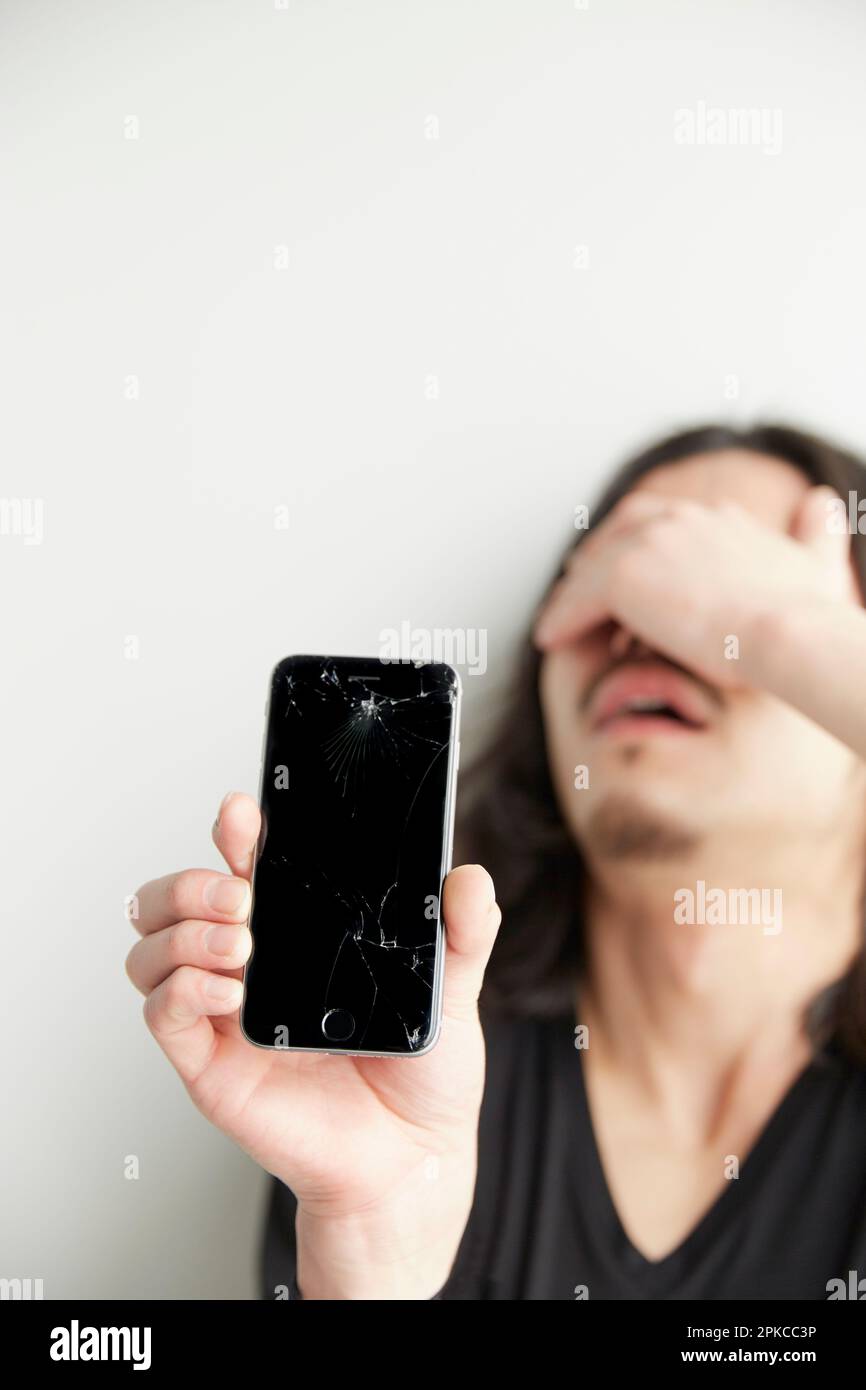 Ein Mann ist deprimiert, weil sein Smartphone-Bildschirm kaputt ist Stockfoto